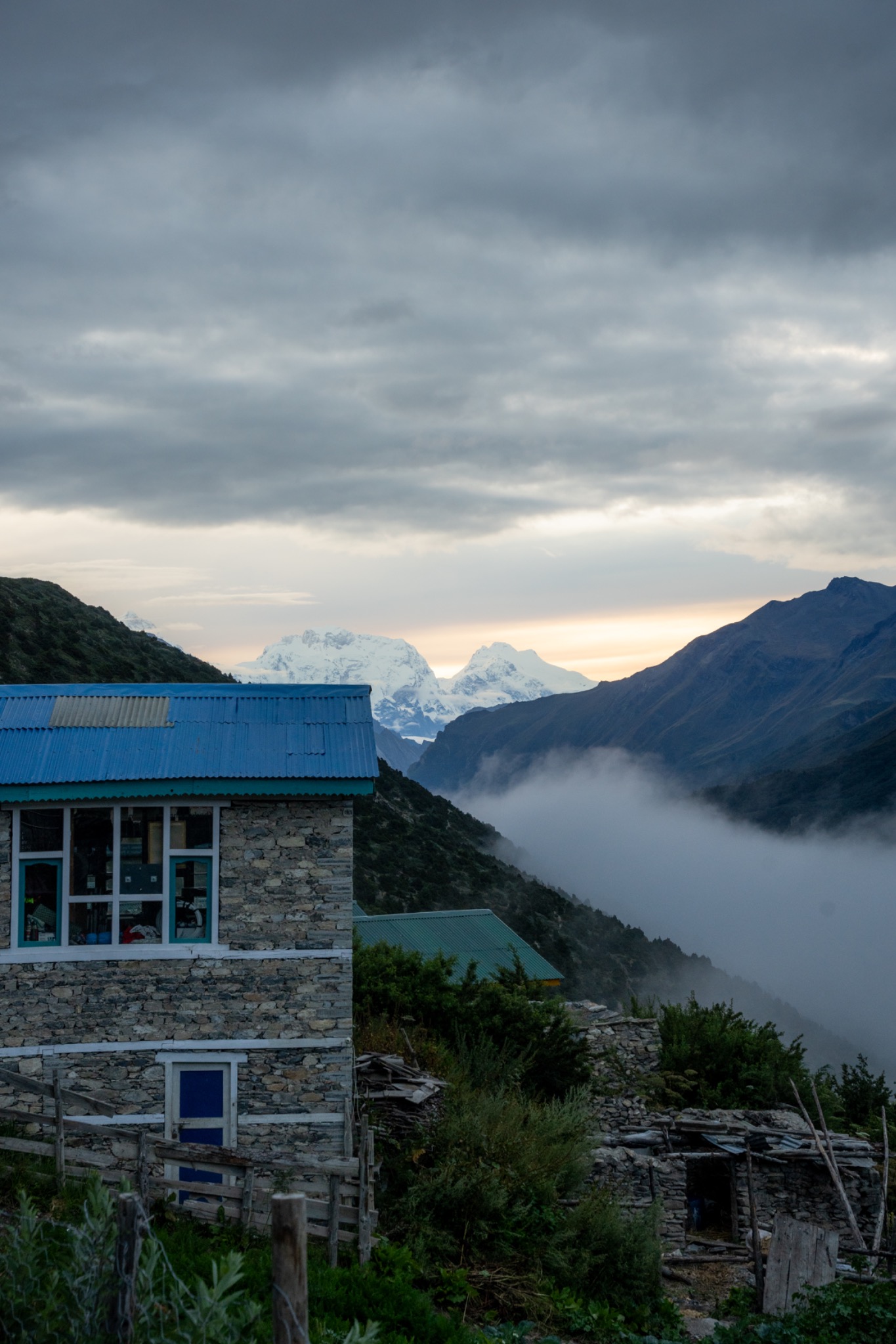 A stone lodge above a cloud-filled valley at dusk
