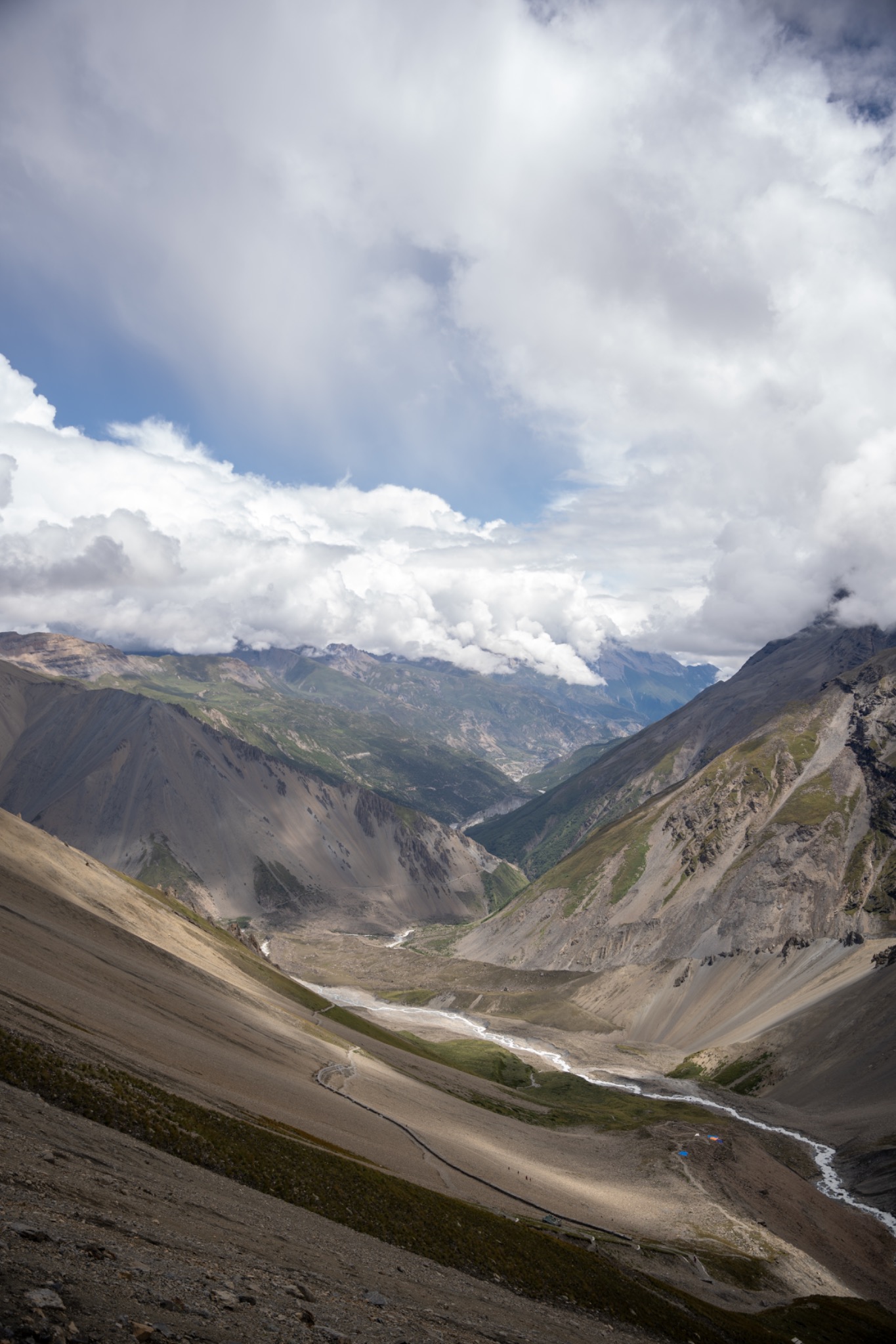 A wide high mountain valley beneath dramatic clouds