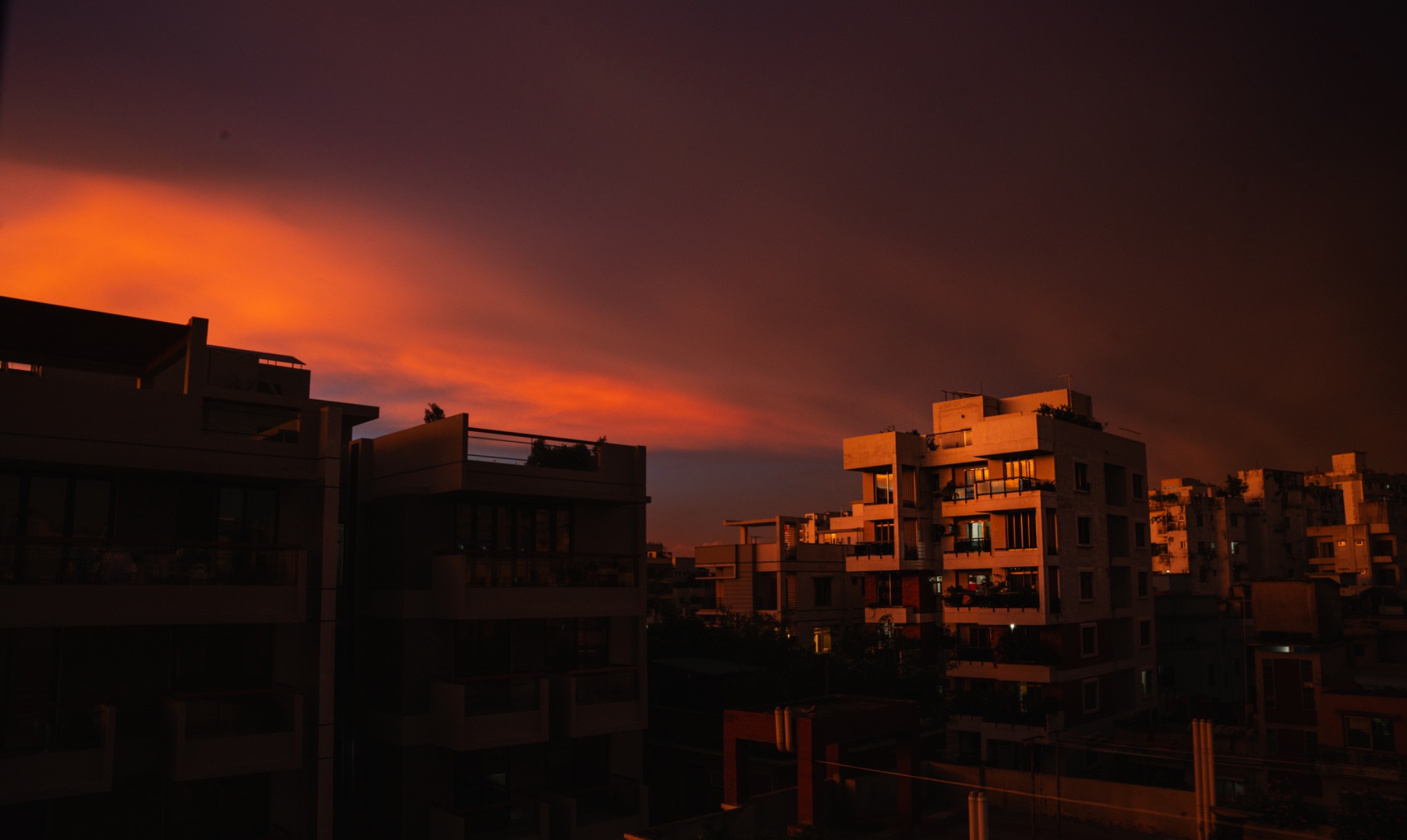 City buildings silhouetted beneath a vivid orange sunset